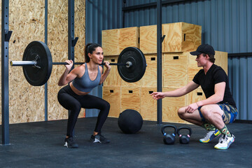 Fototapeta na wymiar Trainer teaching woman to lift weights inside a crossfit GYM