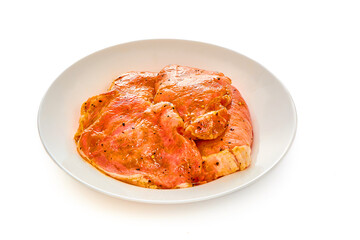 Pork in marinade lies on a white plate on a white isolated background