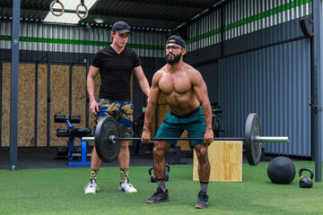 Trainer teaching man to lift weights inside a crossfit GYM