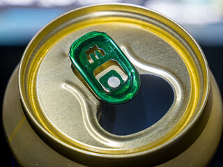 Opened beverage can with green pull tab golden surface