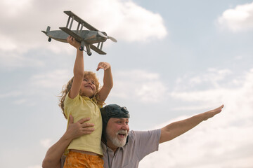 Excited child boy and grandfather having fun with plane outdoor on sky background with copy space....