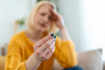 Young woman holding wedding engagement ring in hands, engaged girl doubts about marriage proposal, abandoned wife depressed after getting divorced, help to overcome breaking up, starting new life