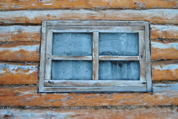 A frozen window in the hunter's house. Glass in ice in the forester's house in the taiga among the trees. Forest.