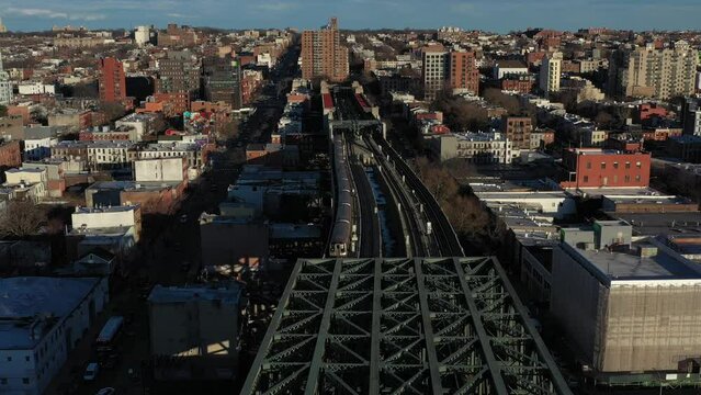 Aerial footage along the elevated train tracks of the Culver Overpass at 9th Street in Brooklyn New York City, with NYC subway train approaching