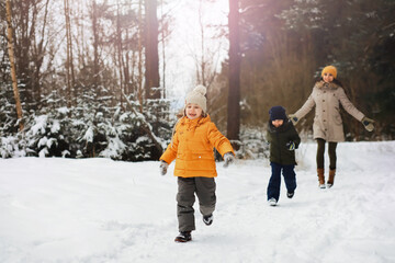 Happy family playing and laughing in winter outdoors in the snow. City park winter day.
