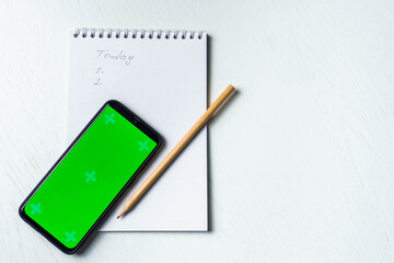 White notepad with inscription today, smartphone green screen mockup and pencil flat lay. Tamplate for design