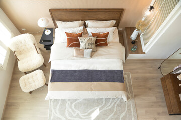 Interior of modern bedroom with white mattress, wooden floor, armchair and small wardrobe. Top view of spacious bedroom.