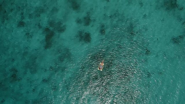 High altitude drone shot of someone floating at the caribbean sea in the Kenepa beach of Curacao