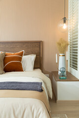Modern bedroom room with stylish comfortable red, brown and yellow pillow on it. Side table lamp.