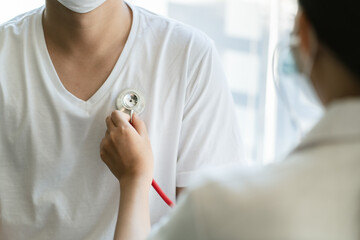 Doctors are using a stethoscope to check lungs and heart in hospital office.