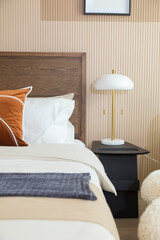 Modern bedroom room with stylish comfortable red, brown and yellow pillow on it. Side table lamp.