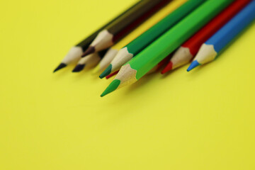 A set of colored pencils lies on a yellow table