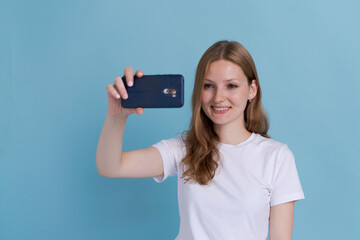 Isolated portrait cheerful young woman in elegant casual clothes making a video call or selfie and waving at the camera. Concept of communication and social networks