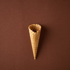 Empty wafer ice cream cone on brown background.