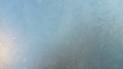 Frozen windshield. Granular structure of transparent ice. The sky is shining through. Abstract ice background.