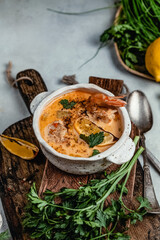 Shrimp soup with herbs, lemon and spices on wooden board, comfort food concept, healthy eating