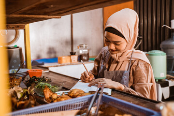 muslim food stall owner write note while working