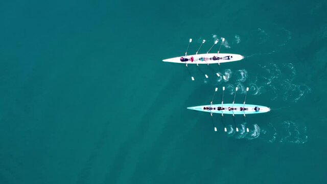 Aerial drone bird's eye view video of two sport canoe operated by team of young men and women . High quality 4k footage