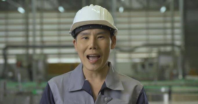 Portrait of male engineer at modern factory. He talking to team and looking to camera. Industry, Engineer and Business concept.