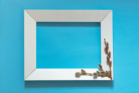 white frame with willow branches on a blue background, blooming buds, happy easter concept