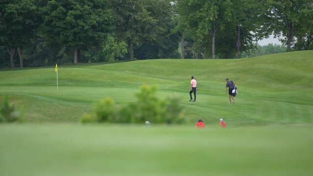 Golfers Approaching the Green with their Caddies on a Golf Course to Putt Their Balls