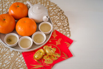 Obraz na płótnie Canvas Chinese New Year festival concept. Mandarin oranges, red envelopes, gold ingots and tea pot with white background. Chinese character 