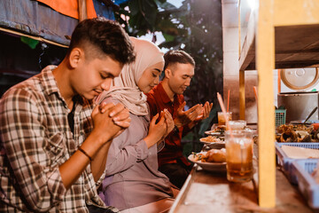 mixed religion people praying before having dinner together