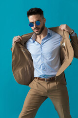 Obraz premium cool retro young man in suit with sunglasses adjusting jacket