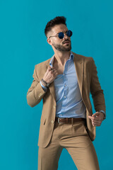 seductive young man in beige suit pulling shirt in a sexy way