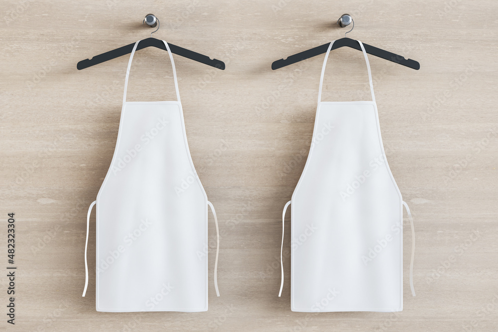 Aufkleber empty white kitchen aprons on hangers. light wood background. chef and cooking concept. mock up plac