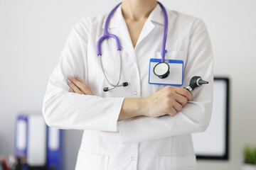 A otolaryngologist in a white coat holds an otoscope