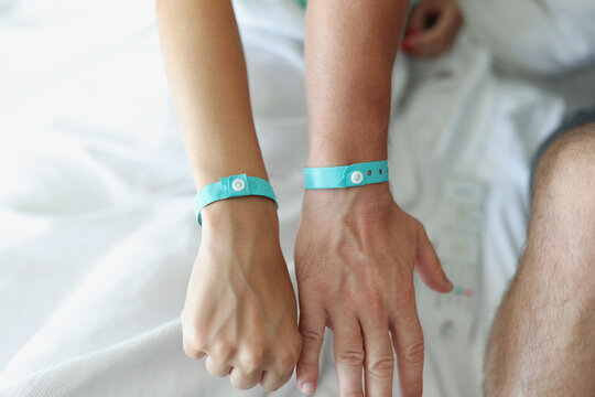On the male and female hands a blue hotel bracelet