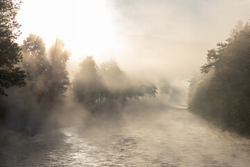 river in fogg, sunlight comes through the foggy air, golden hour in the morning, warmlight in the cold