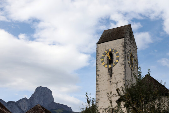 Alte Kirche unter blauem Himmel, bew&ouml;lkt, kirchenuhr, b&auml;ume, berge, wolken,