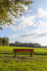 rote Sitzbank im gründen, auf Feld, leicht bewölkt, herbst