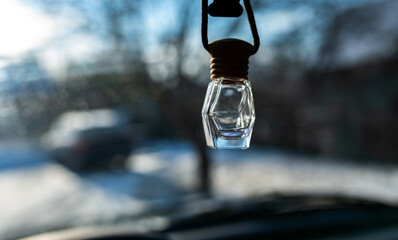 Empty, hanging car air glass freshener on a bright sunny winter day close up shot, shallow depth of field, space for text.