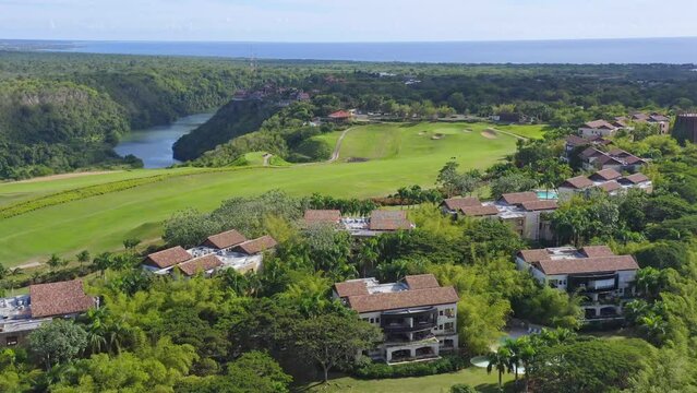 Aerial forward over residential and luxury houses in countryside and golf course in background. Altos de Chavon, La Romana in Dominican Republic