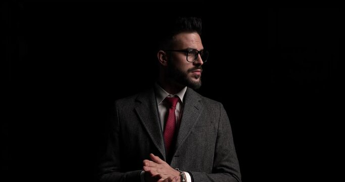 sexy businessman rubbing his palms, arranging his glasses and suit then disappearing into the dark
