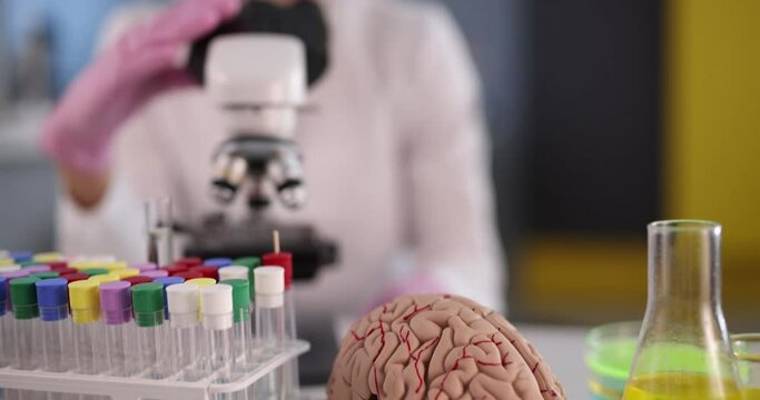 Scientist chemist doing microscopic examination in front of artificial model of human brain in laboratory 4k movie