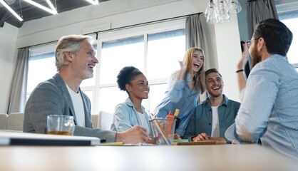 Two cheerful young business people giving high-five while their colleagues looking at them and smiling