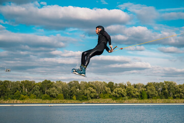 Man practicing technique of jumping over water with rotation during wakeboarding training