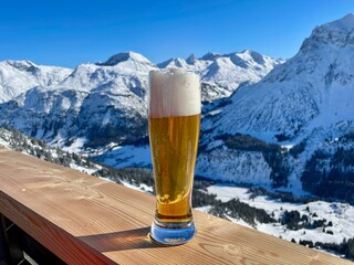 Apres ski in the Austrian Alps. Glass of wheat beer on wooden fence on a sunny day. Lech Zuers...