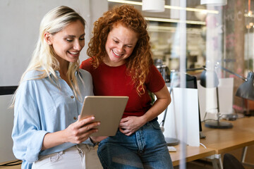 Happy smiling business women working together online on a tablet in office