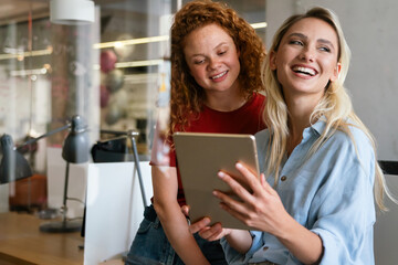 Happy smiling business women working together online on a tablet in office