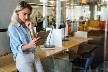 Portrait of happy successful woman working, websurfing on digital tablet in office