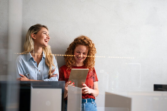 Portrait of happy business people having fun and using digital tablet at workplace office