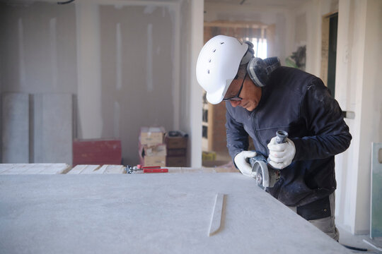 Construction worker cutting sheetrock with power tool at site