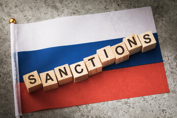 Wooden cubes with text and a flag on a concrete background, the concept of sanctions in Russia