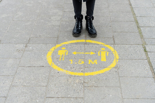 Woman standing near social distance marking on pavement