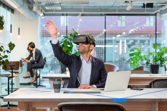 Manager wearing VR googles and gesturing in modern office
